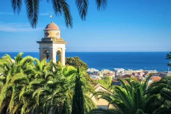 Vista panoramica di una torre tra palme con il mare all'orizzonte.