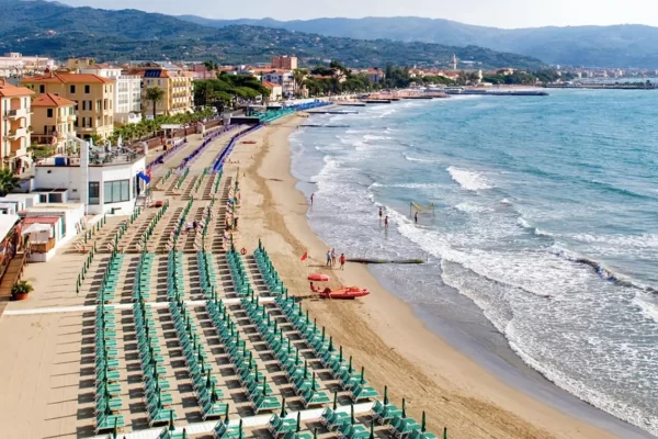 Spiaggia attrezzata con file di lettini e ombrelloni lungo la costa.